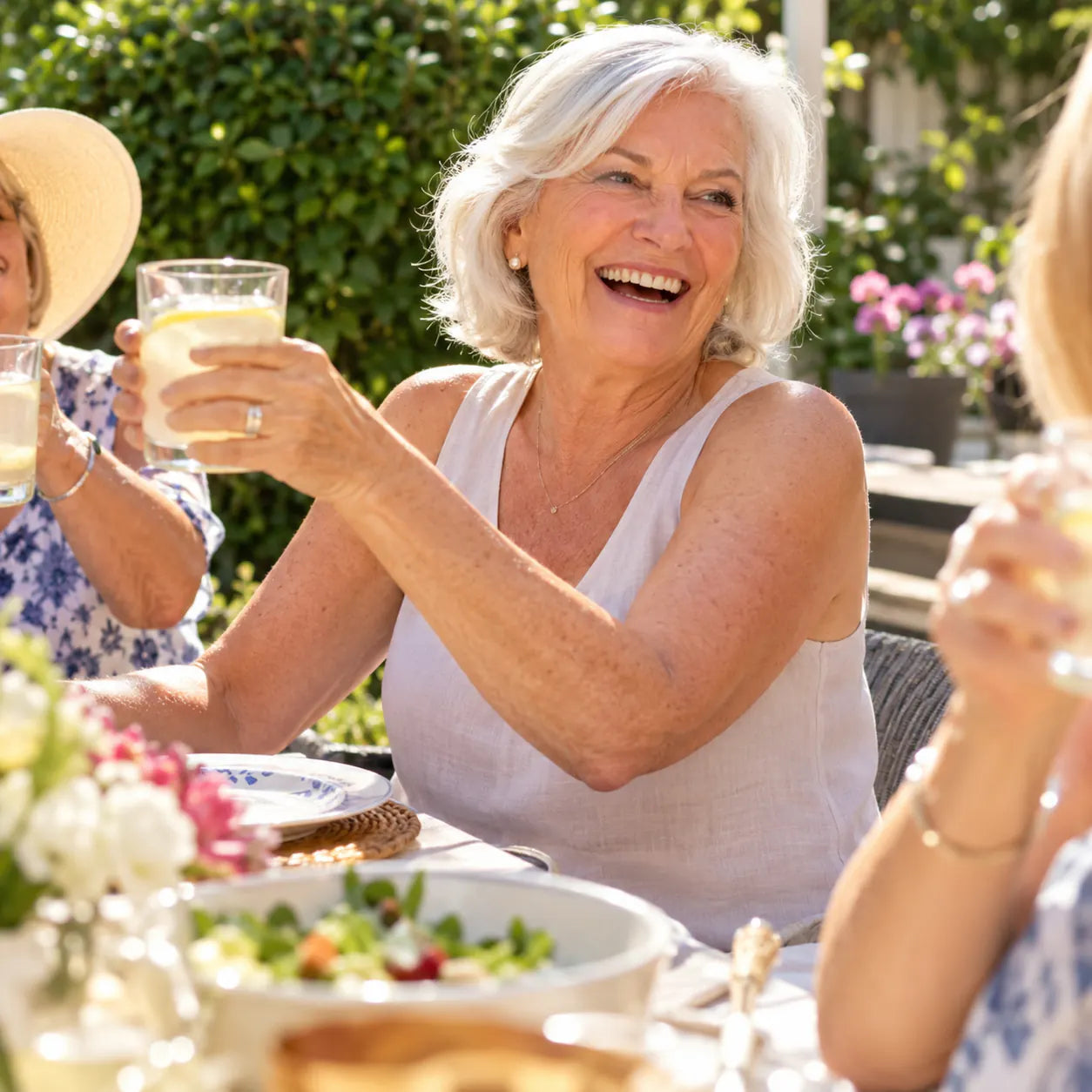A woman about 70 laughing in a sleeveless top, bare arms smooth and even